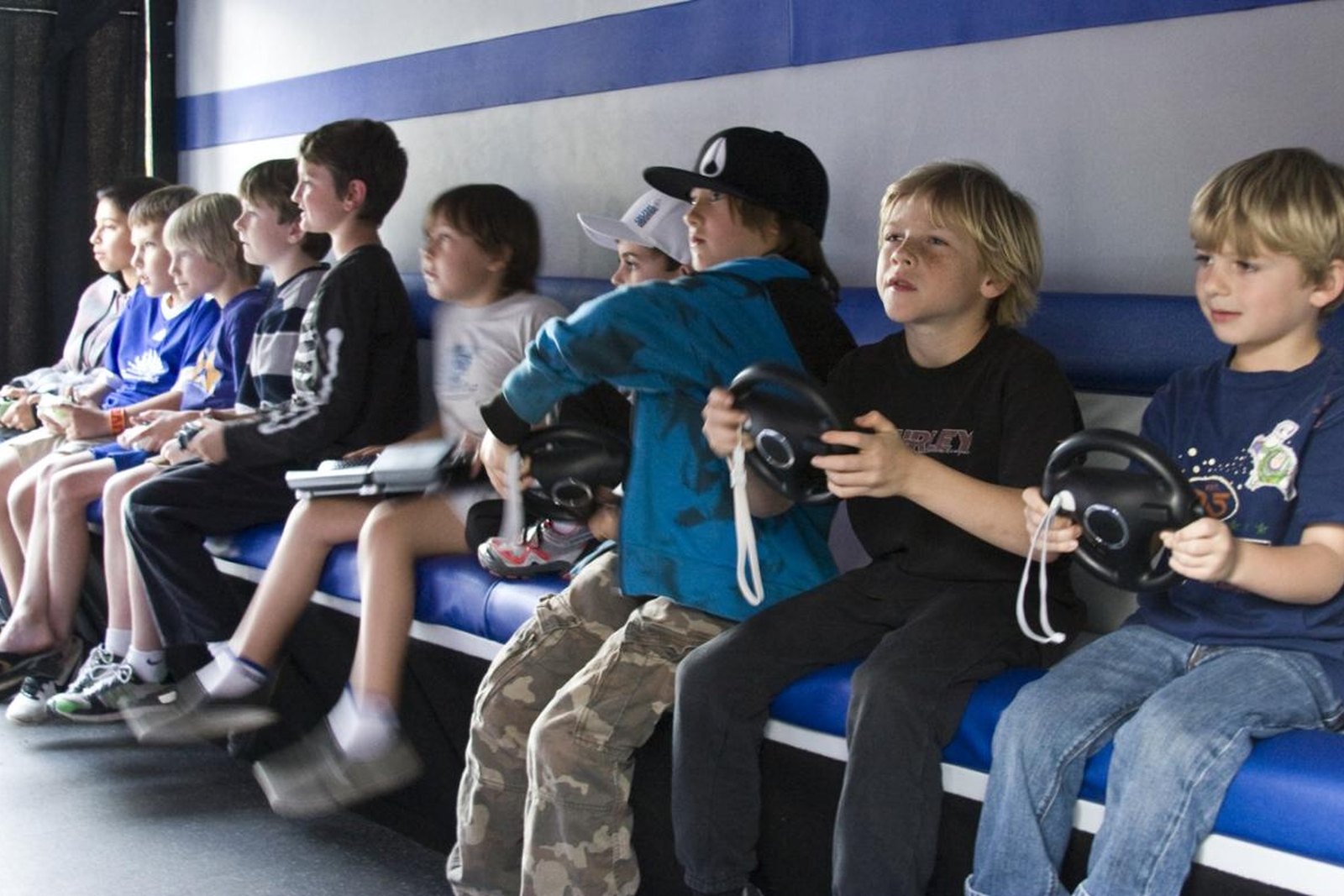 Kids sitting in a row playing console games together at a family gaming club